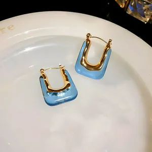 Close-up detail of vintage light blue and gold U-shaped hoop earrings on a plate