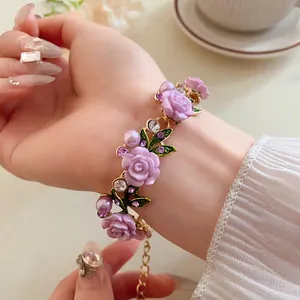 Elegante bracciale con rose viola, perle e strass sul polso di una modella in stile country