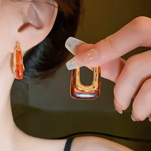 Macro view of vintage amber resin U-shaped hoop earrings featuring a gold metal frame.