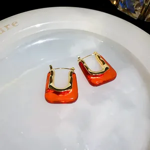 Close-up of vintage U-shaped hoop earrings featuring orange resin and gold metal textures