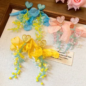 Dettaglio orecchini cuore in chiffon con nappe in blu, rosa e giallo fatti a mano