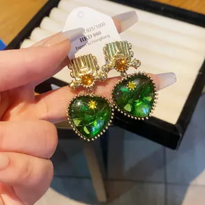 Close-up of vintage heart-shaped green earrings with golden geometric top detail