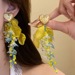 Dettaglio degli orecchini a nappa in chiffon giallo con cuori dorati per le vacanze