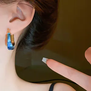 Close-up of vintage U-shaped hoop earring with blue gradient glaze finish on model ear