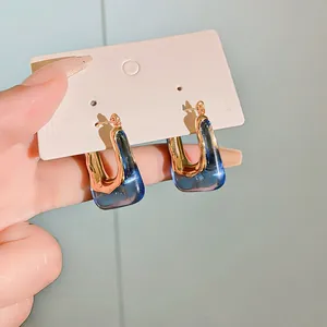 Detailed view of retro U-shaped hoop earrings featuring blue resin and gold finish