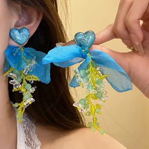 Primo piano di orecchini con nappe a cuore in chiffon blu e dettagli in rilievo