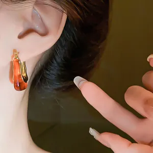 Close-up of vintage U-shaped amber resin hoop earrings with gold wavy metal edge