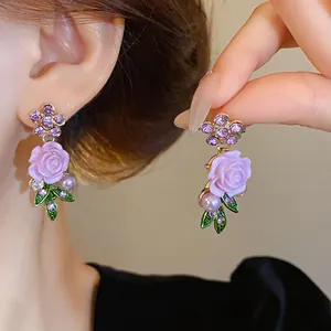 Primo piano di eleganti orecchini a rosa viola con perle lavanda e dettagli in cristallo