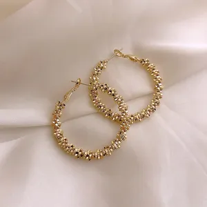 Macro view of gold hoop earrings featuring a unique crushed ice textured design on silk