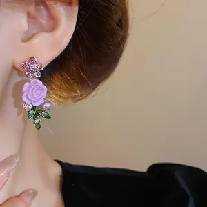 Primo piano di orecchini a fiore viola con cristalli e perle indossati all'orecchio