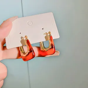 Detailed macro view of vintage U-shaped hoop earrings featuring red resin and gold plating
