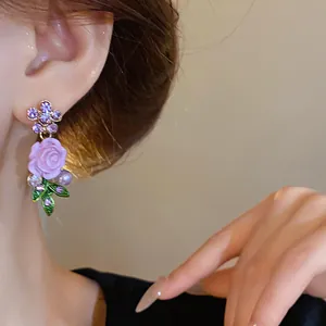 Dettaglio ravvicinato di eleganti orecchini floreali a rosa viola con strass all'orecchio