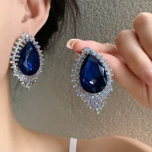 Elegant dark blue teardrop earrings with sparkling halo rhinestone details worn by model