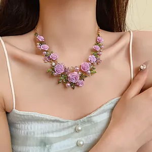 Dettaglio di una collana pastorale a fiori con rose viola e perle su una modella