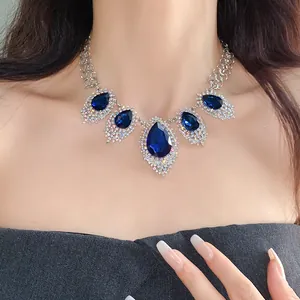 Close-up detail of luxury blue water-drop crystal statement necklace worn by elegant model