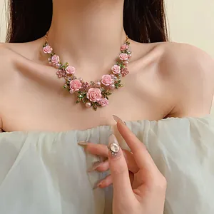 Dettaglio di una collana di fiori rosa in stile pastorale con perle indossata da un modello