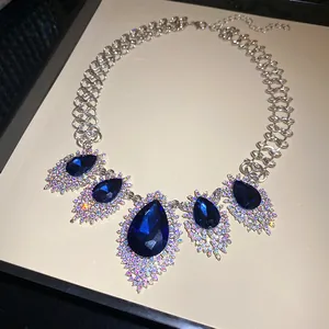Close-up of elegant silver necklace featuring large blue teardrop crystals and AB rhinestones.