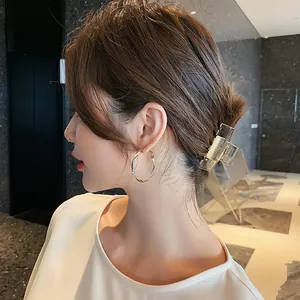 Close-up view of a model wearing elegant gold twisted hoop earrings and a hair claw clip