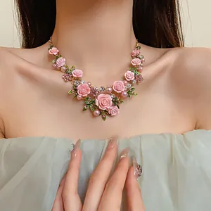 Primo piano di una collana floreale rosa con perle e strass indossata da una modella