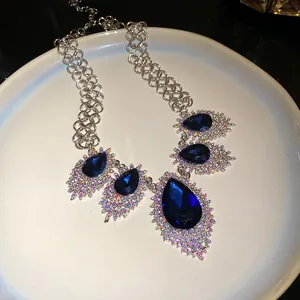 Detailed macro view showing sparkling dark blue teardrop crystals on a silver necklace