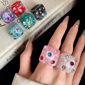 Chunky colorful resin rings with sparkling inlaid rhinestones worn on fingers.