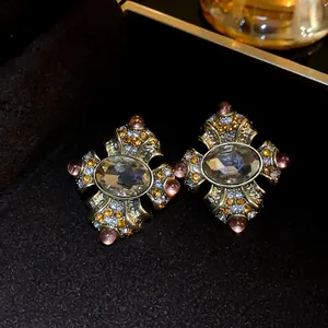 Close-up view of vintage palace style stud earrings with multifaceted stones and aged gold finish