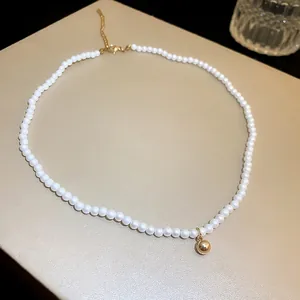 Elegant white pearl choker necklace featuring a polished gold ball pendant detail