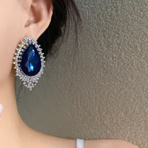 Detailed close-up of luxurious blue teardrop rhinestone earring on model's ear