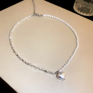 Elegant close-up detail of a silver heart pendant on a pearl and metal chain necklace