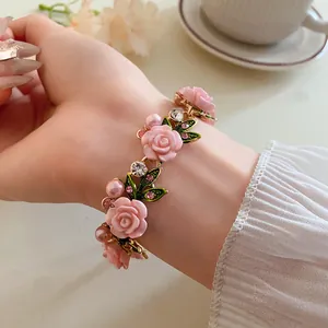 Dettaglio di un braccialetto con rose rosa, perle e strass indossato sul polso.