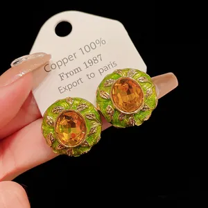 Close-up of vintage court style geometric earrings with green enamel and amber stones.
