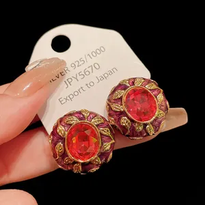 Macro detail of vintage court style earrings featuring red gemstone and purple enamel