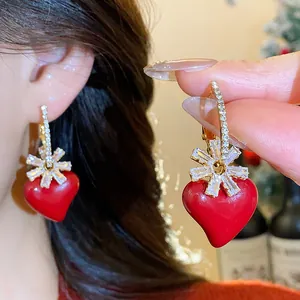 Vue détaillée des élégantes boucles d'oreilles cœur rouge ornées d'une fleur en zircon brillant.