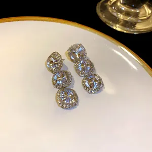 Macro view of sparkling triple-round rhinestone drop earrings on an elegant plate.