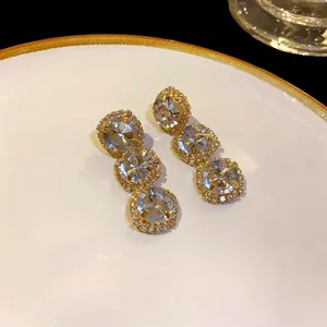 Elegant three-tier round crystal drop earrings with sparkling pavé border in gold