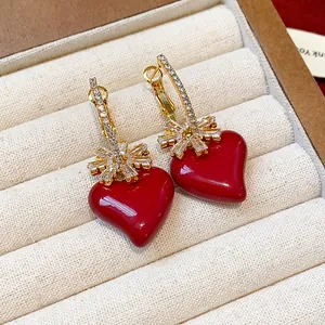 Gros plan de boucles d'oreilles cœur rouge plaquées or 18 carats avec fleurs en zircon.
