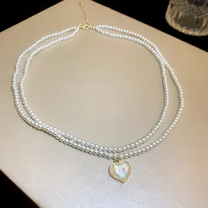 Close-up detail of a double-strand pearl necklace featuring a glowing heart-shaped pendant.