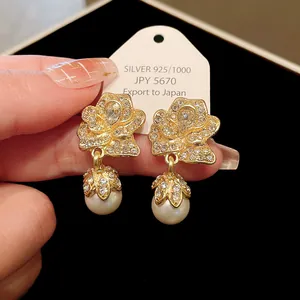 Close-up of vintage court-style gold rose earrings with crystals and hanging pearls