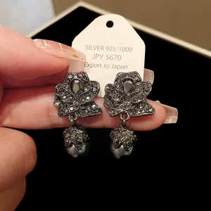 Close-up of vintage dark rose earrings with grey pearl drops and silver 925 tag.
