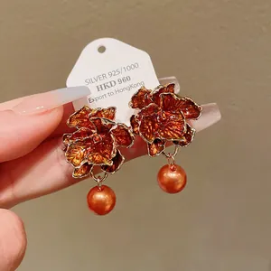 Exquisite close-up of vintage flower earrings with orange enamel petals and pearl drops