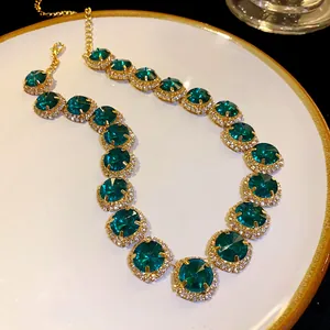 Detail view showing emerald green crystals on a gold-plated necklace