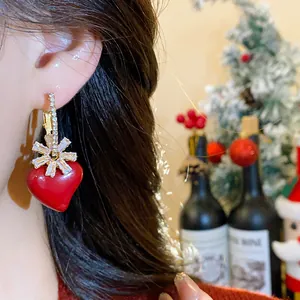Gros plan d'élégantes boucles d'oreilles cœur rouge plaquées or 18 carats avec fleurs.
