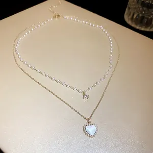 Elegant detail view of a double-layered necklace featuring a pearlescent heart pendant and pearls