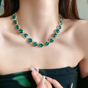 Detailed view of luxury emerald green crystal necklace with diamond halo on model
