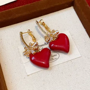 Gros plan de boucles d'oreilles cœur rouge avec nœud en zircon plaqué or 18 carats