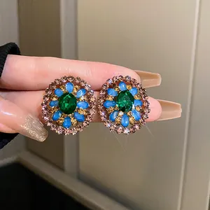Detailed view of vintage palace style earrings with green, blue, and amber rhinestones.