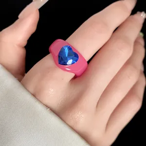 Close-up of a pink resin ring featuring a brilliant blue heart-shaped rhinestone