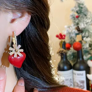 Gros plan d'élégantes boucles d'oreilles cœur rouge avec détails en zircon sur modèle