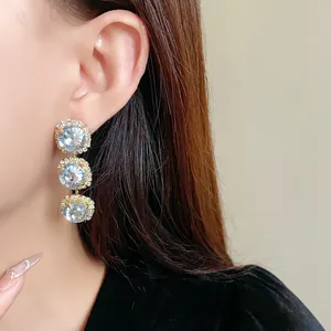 Detailed view of elegant triple-tier rhinestone dangling earrings worn by a model