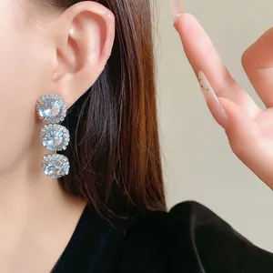 Elegant close-up view of triple round brilliant-cut crystal drop earrings being worn on the ear